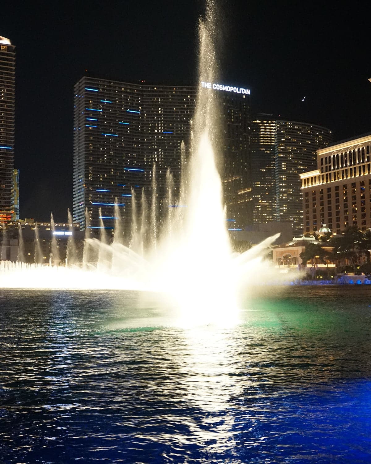 The Bellagio fountains firing at night in front of the Cosmopolitan.